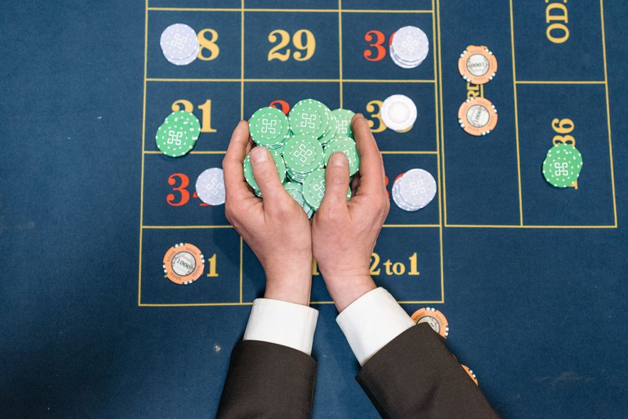 Tangan pemain menyusun chip poker di atas meja permainan