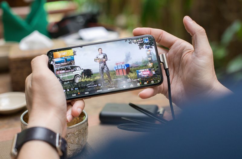 Pengguna bermain game di smartphone sambil bersantai